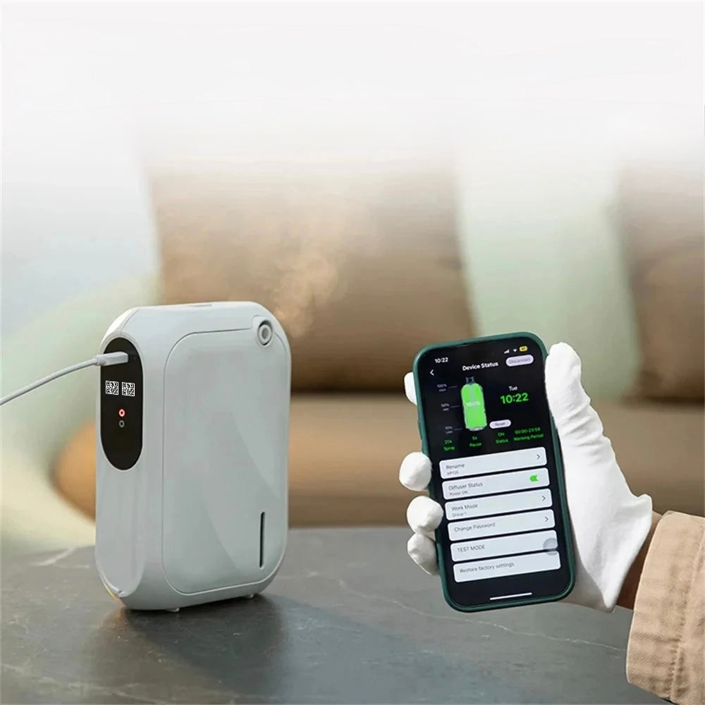 A white electronic aromatherapy device is on a table with a smartphone displaying an app interface.