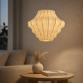 Warm cream wabi sabi ceiling shade with a faceted lantern shape glowing above a side table with a vase and a book