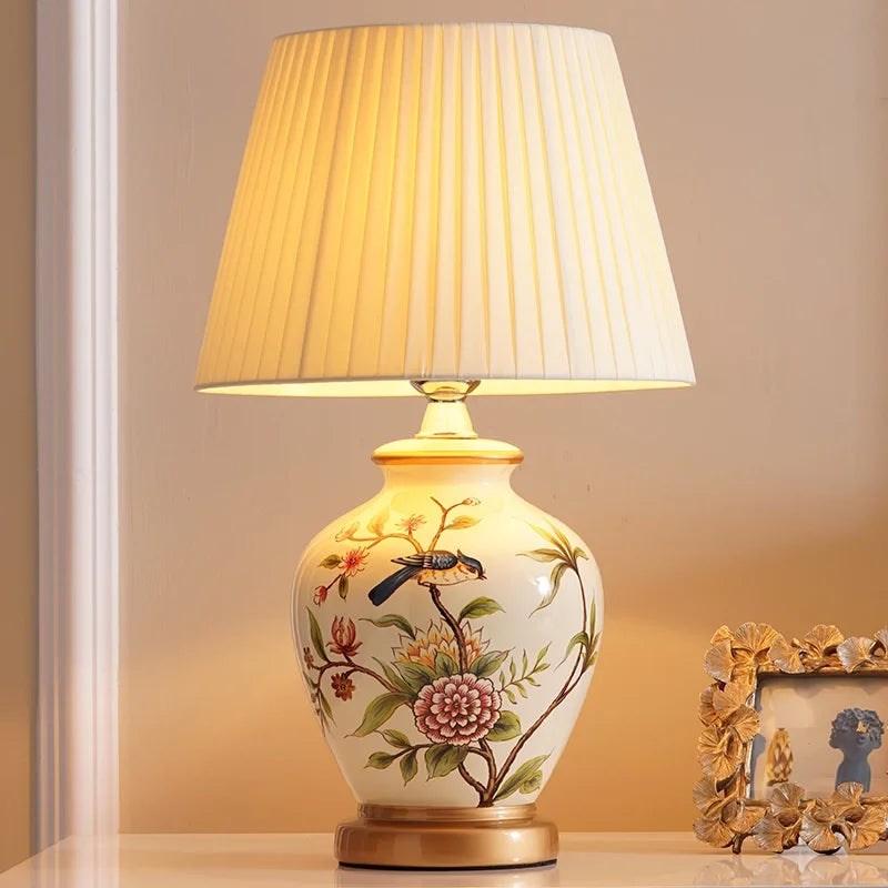 Cream ceramic table lamp with bird and flower artwork and pleated cream shade