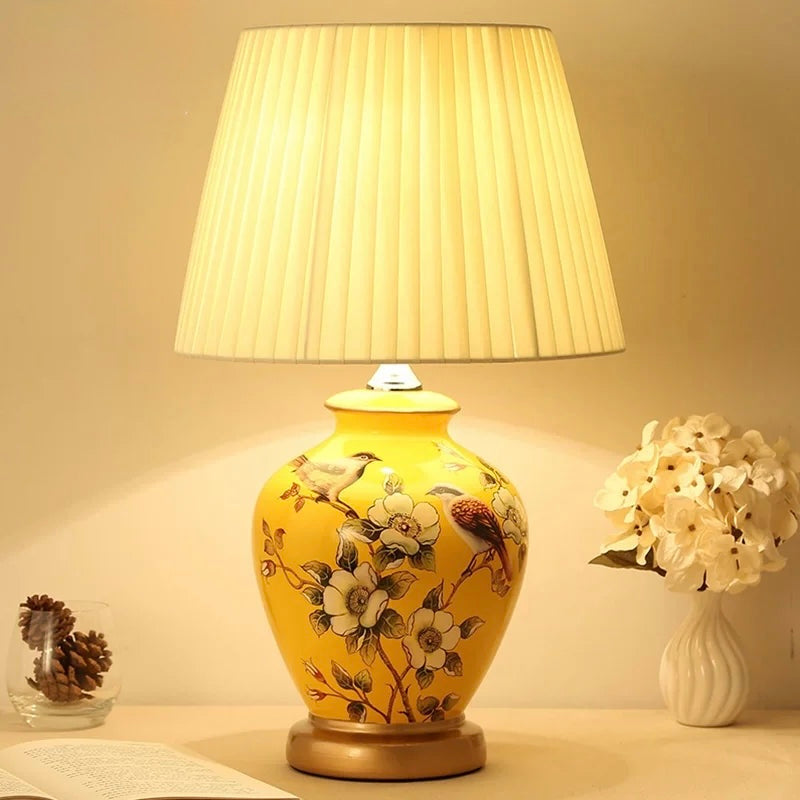 Yellow ceramic table lamp with bird and blossom artwork and pleated cream shade