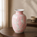 Pink ceramic vase with floral patterns on a wooden table