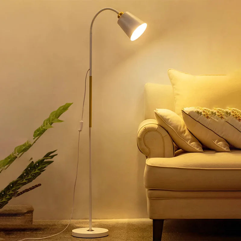A white modern floor lamp beside a sofa, casting warm ambient light in a living room