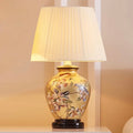 Antique gold ceramic table lamp with bird and floral artwork and pleated cream shade