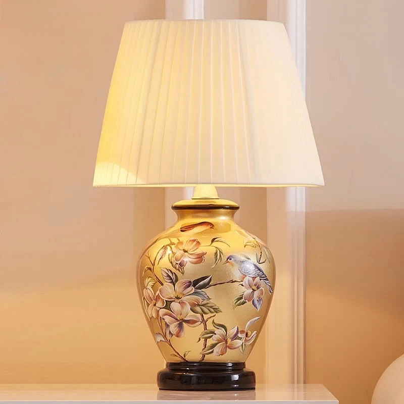 Antique gold ceramic table lamp with bird and floral artwork and pleated cream shade
