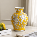 Yellow vase with floral patterns on a table next to books
