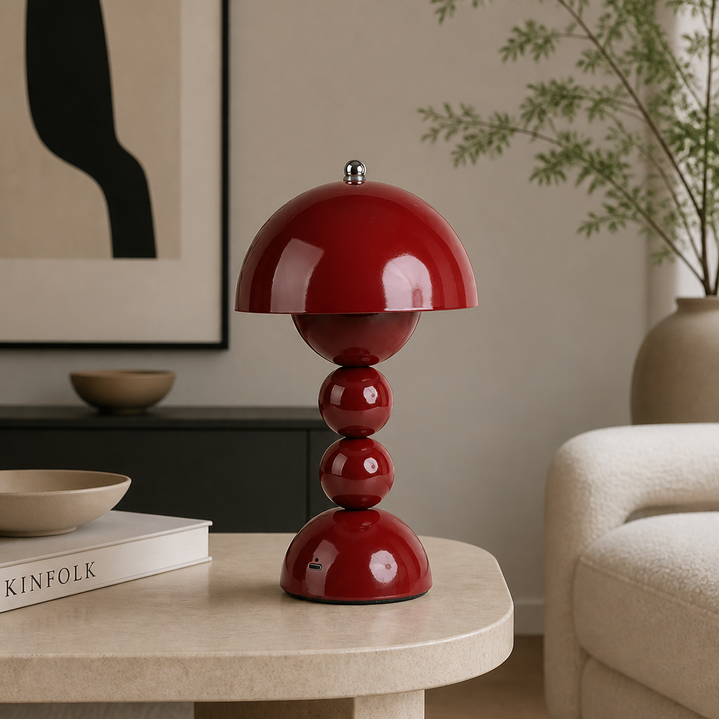A glossy red mushroom-shaped table lamp sits on a light beige round table in a modern living room setting.