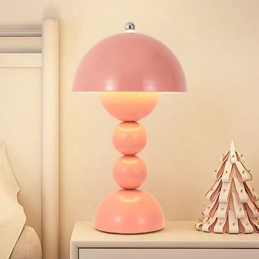 Pink table lamp on a nightstand with a decorative item in the background