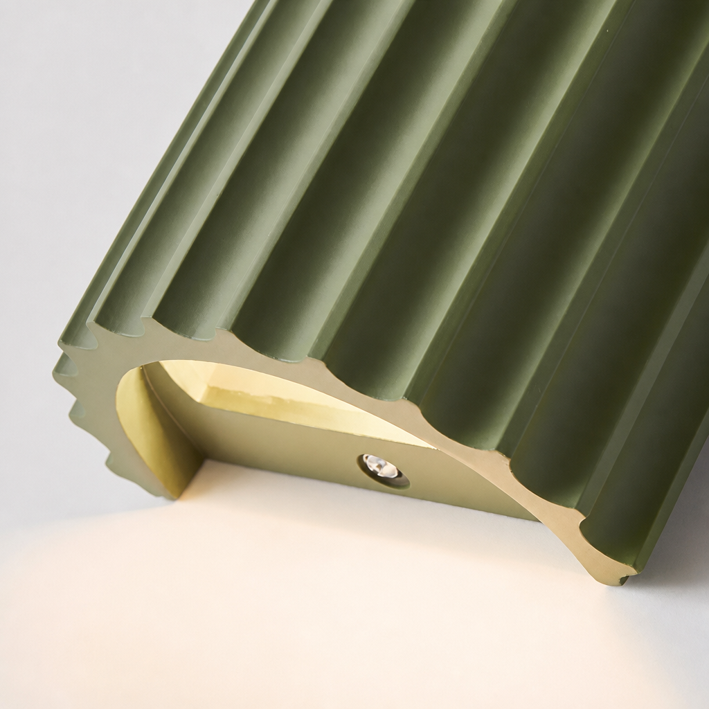 Close-up os a sage green ribbed resin wall lamp with minimalist fluted design.