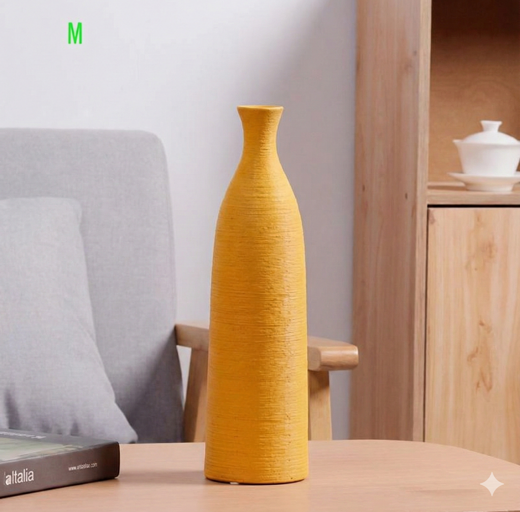 Yellow vase on a wooden table with a grey cushioned chair and wooden cabinet in the background.