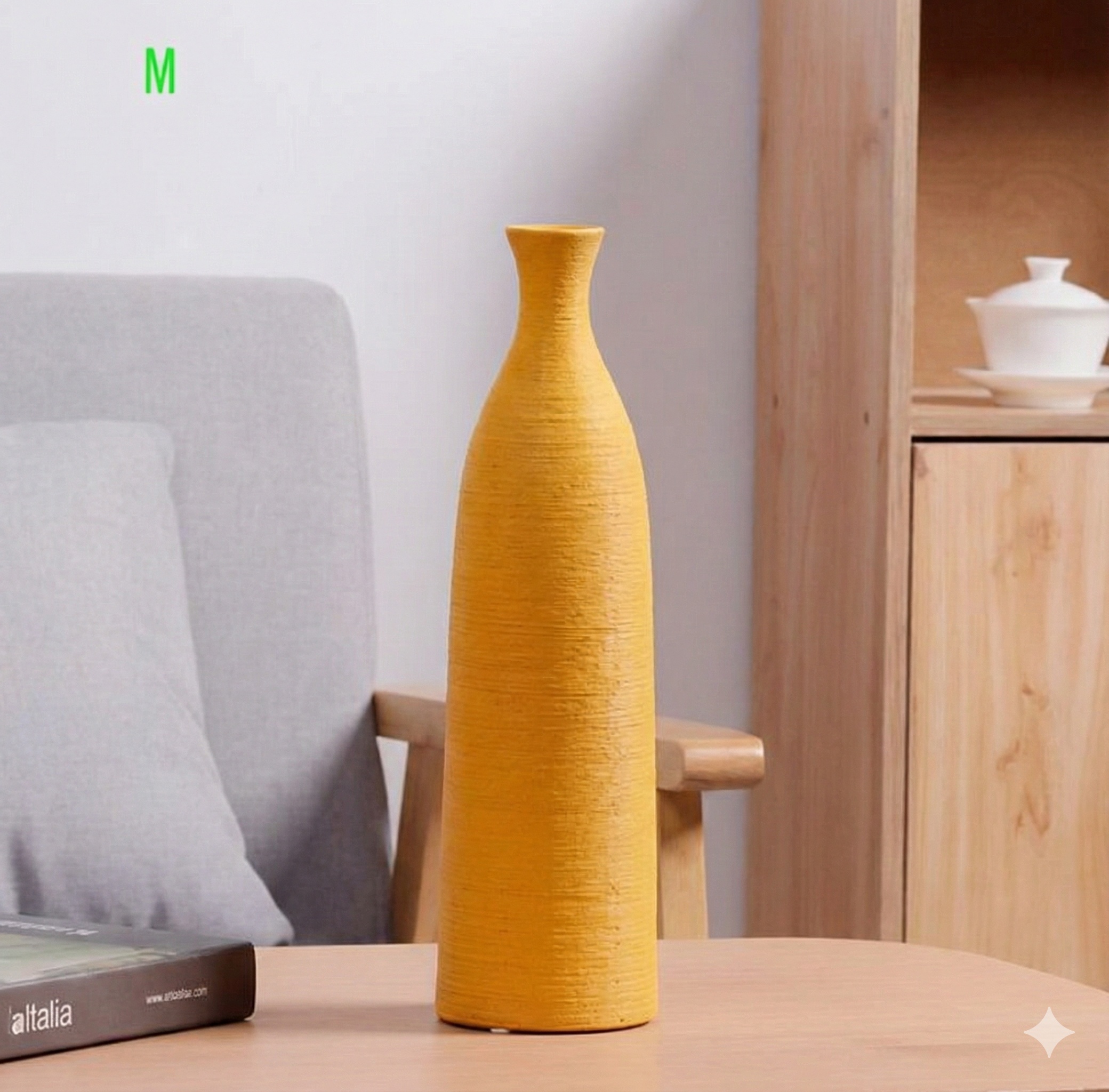 Yellow vase on a wooden table with a grey cushioned chair and wooden cabinet in the background.