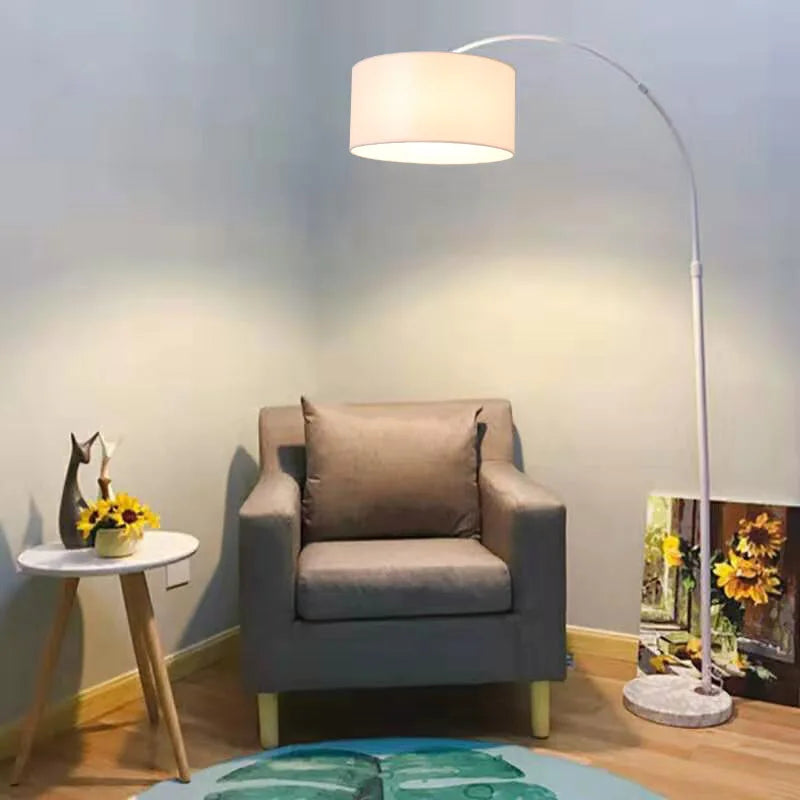 A white arc floor lamp overhanging a grey armchair in a cosy living room setting.