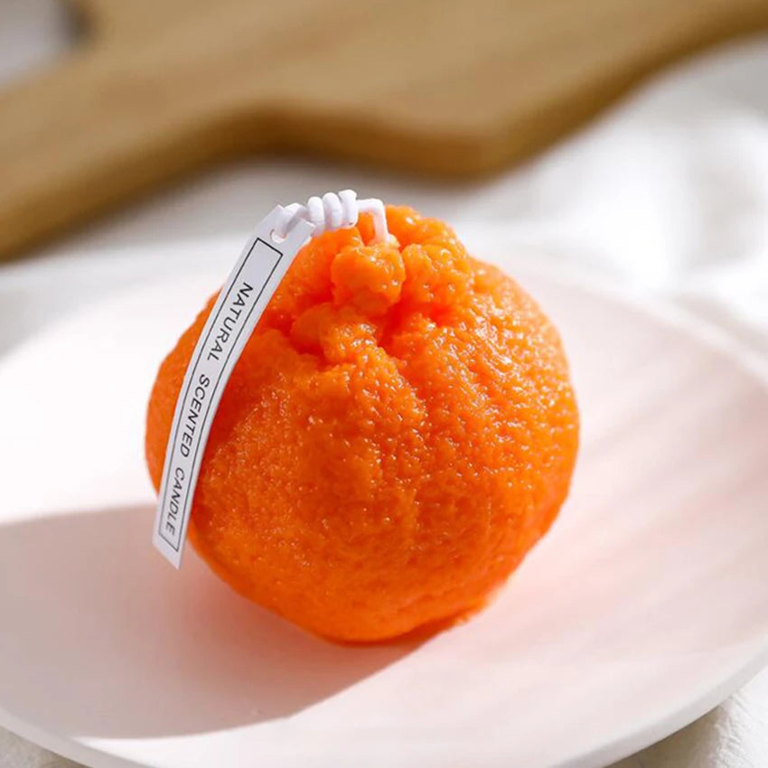 Orange scented candle on a white plate with a wooden background