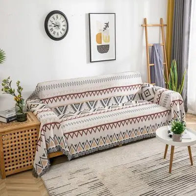 Full view of a retro-style sofa throw with fringed edges draped over a cream-coloured couch.