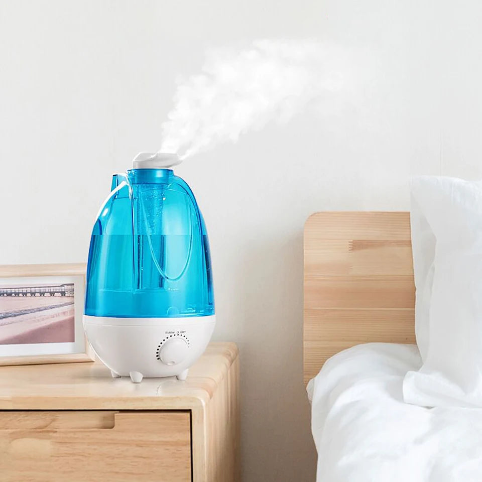 Blue humidifier on a nightstand with steam coming out, next to a bed.