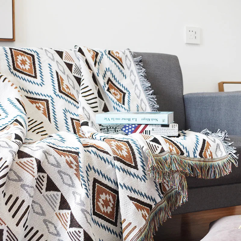 Patterned throw blanket draped over a sofa with books on top