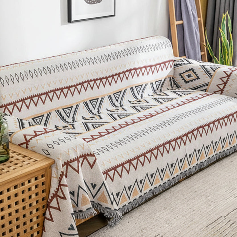 Full view of a retro-style sofa throw with fringed edges draped over a cream-coloured couch.