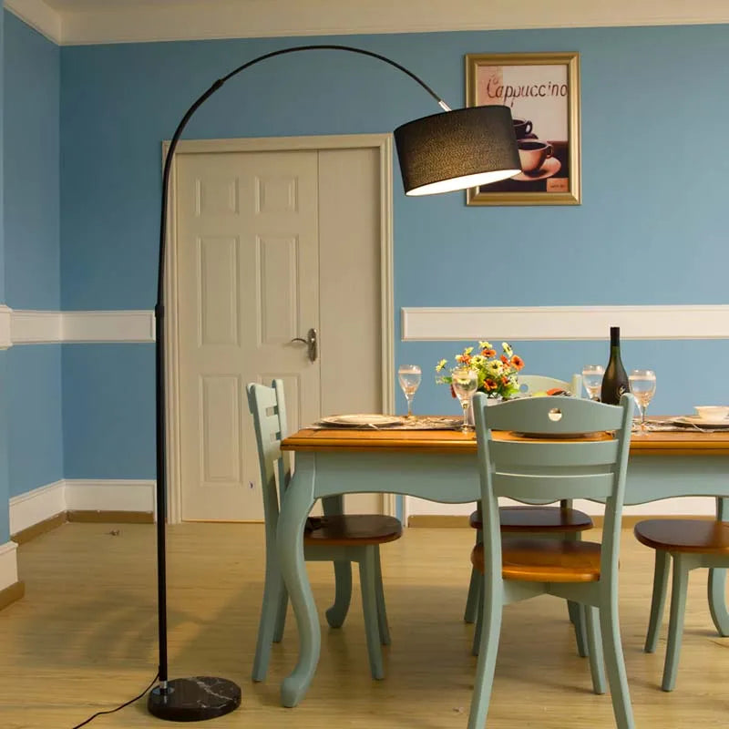 Dining room with a table, chairs, and a standing lamp against a blue wall.