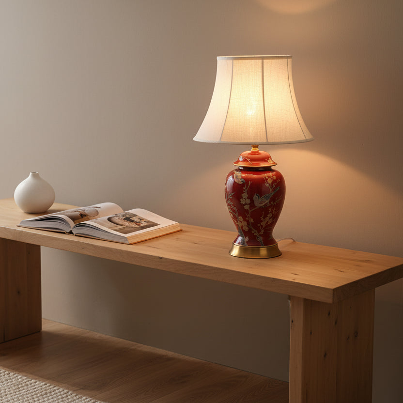 Decorative table lamp on a wooden surface with a book and small white vase.