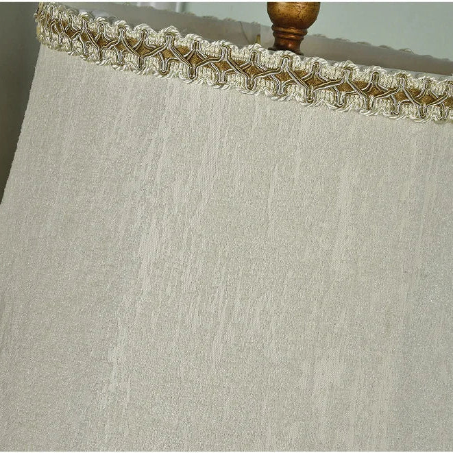 Textured lampshade with decorative trim on a neutral background