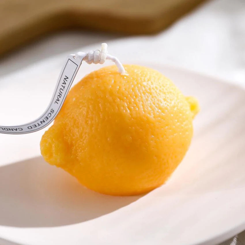 Lemon-shaped candle on a white plate with a blurred background