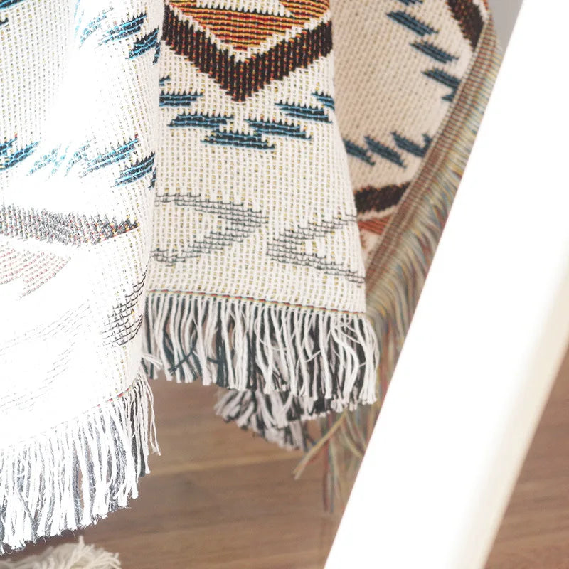 Textile sofa cover with geometric pattern and fringes on a wooden surface