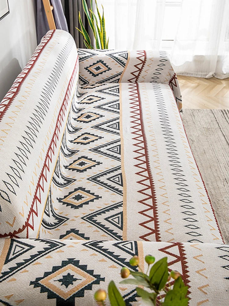 Close-up of a woven geometric pattern throw with cream, black, and tan earth tones on a sofa.