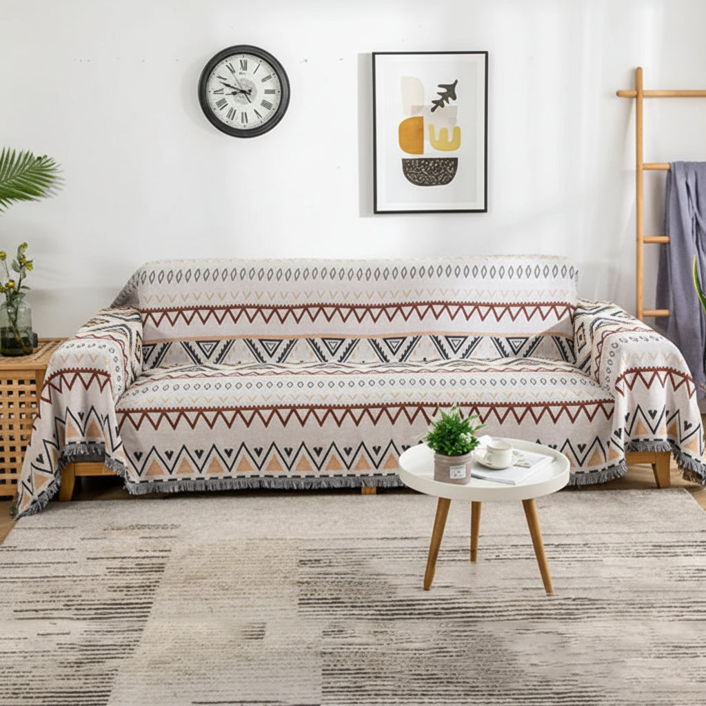 Full view of a retro-style sofa throw with fringed edges draped over a cream-coloured couch.