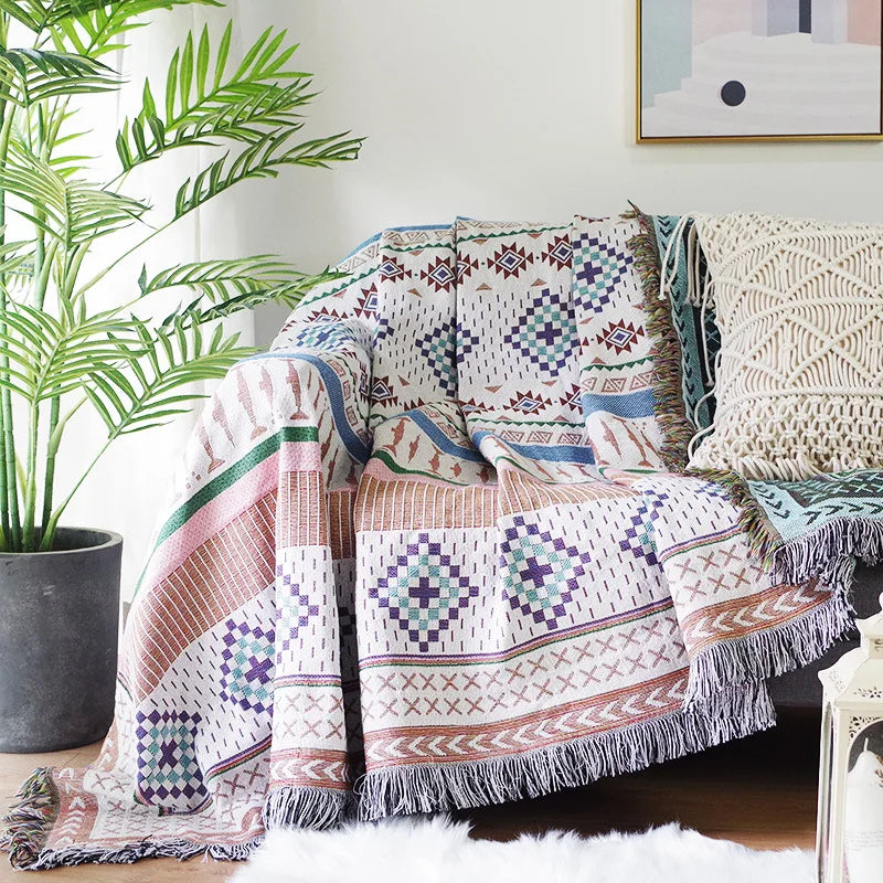 Pastel Patchwork Aztec throw layered over a cream sofa beside a macrame cushion.