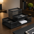 Black mesh desk organizer on a wooden surface with office supplies.