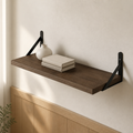 Dark wooden shelf with black brackets holding a vase and books against a light wall.