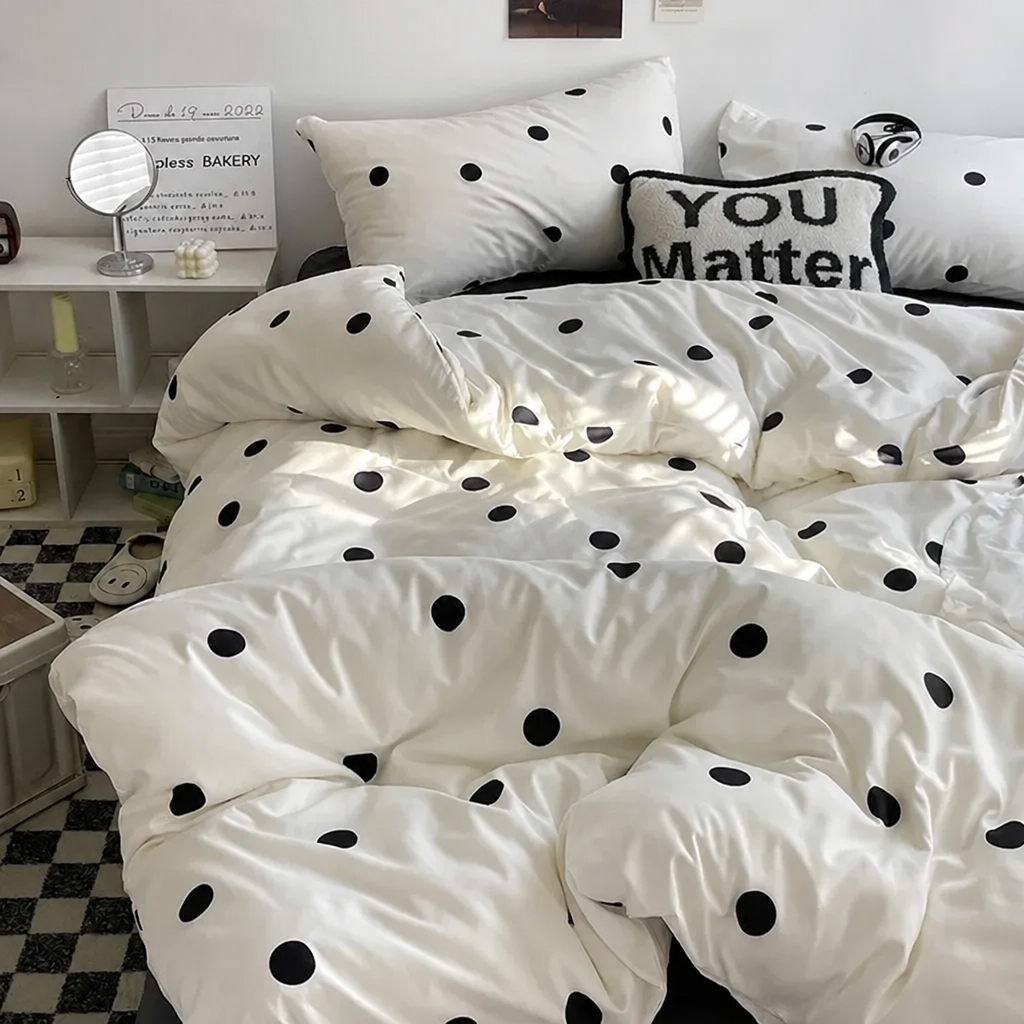 White bedding set with black polka dots styled with decorative pillows