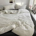 Cream bedding set with thin pinstripes on a bed beside a window