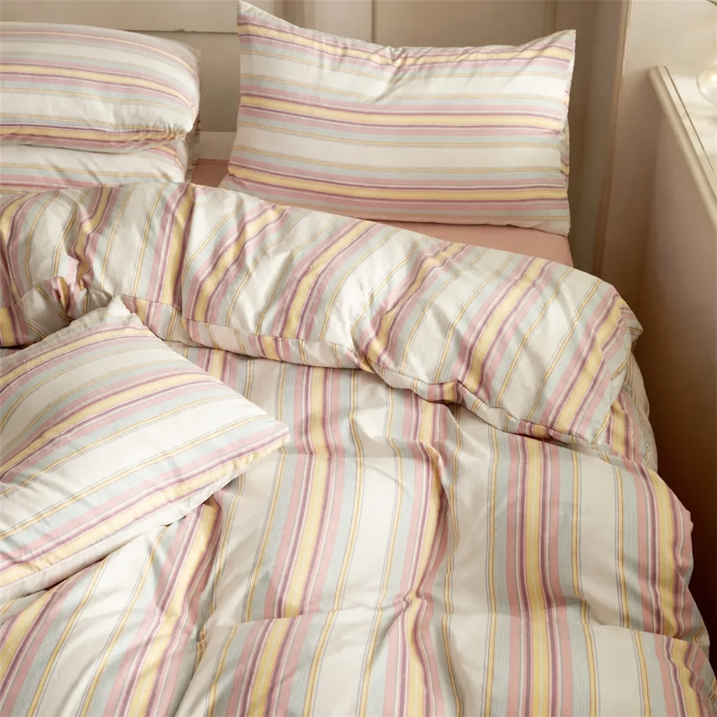 Striped bedding set with pink and yellow lines on a bed.
