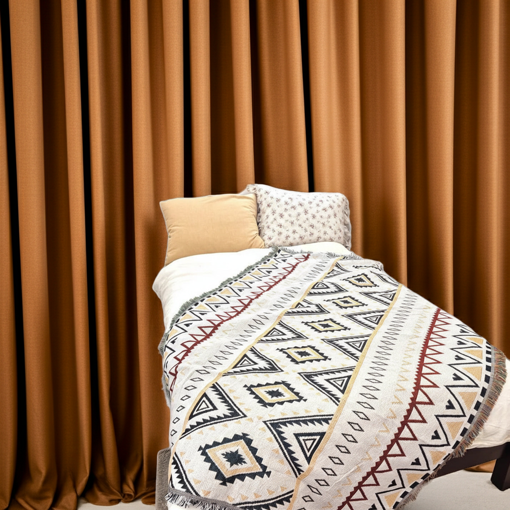 Bed with patterned quilt and pillows against a brown curtain background