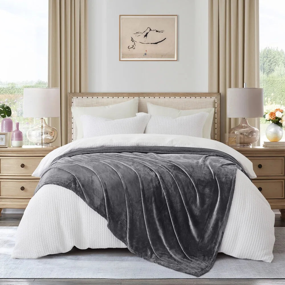 A grey blanket draped over a bed in a stylish bedroom with decor elements.
