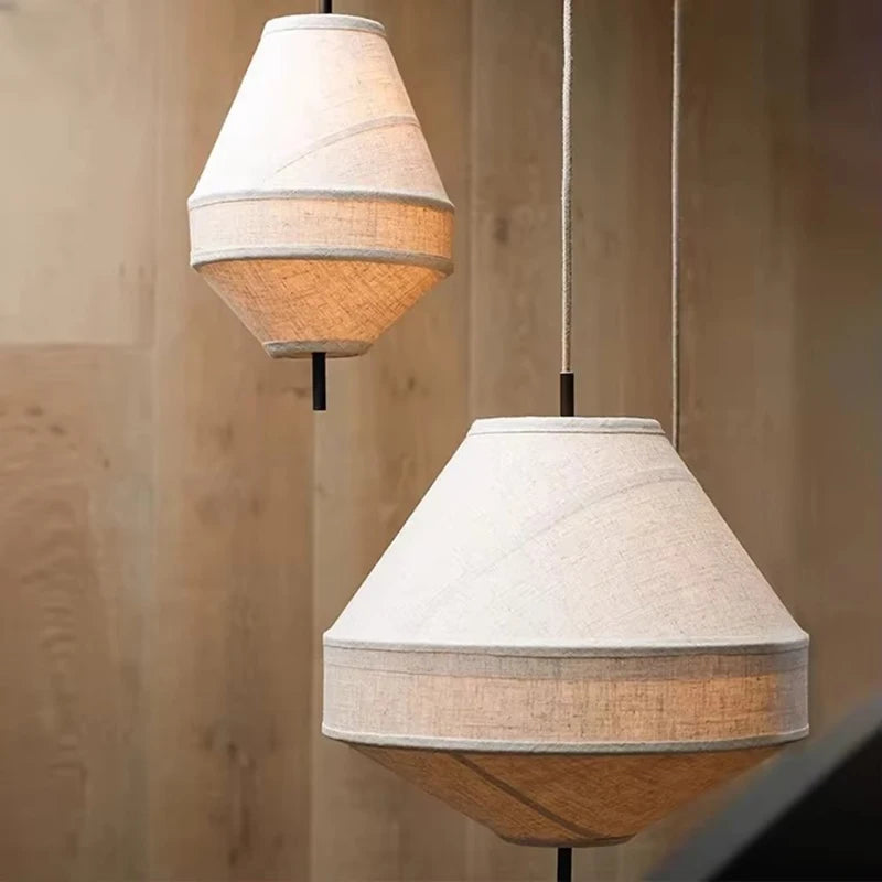Two pendant lights with fabric shades hanging against a wooden panel background