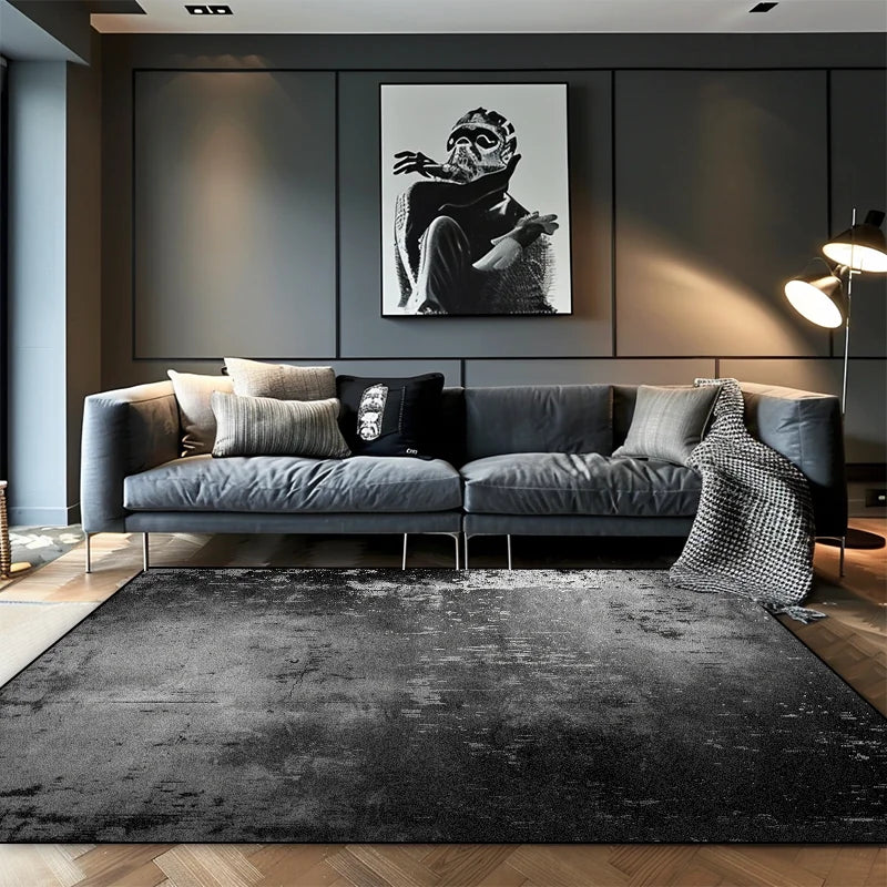 Deep charcoal ombre abstract area rug with subtle distressed texture in a moody contemporary living room with grey sofa
