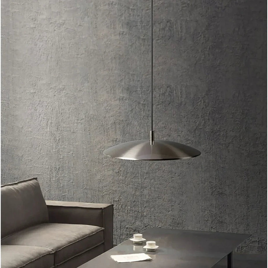 Modern living room with a gray sofa, coffee table, and pendant light against a concrete wall.
