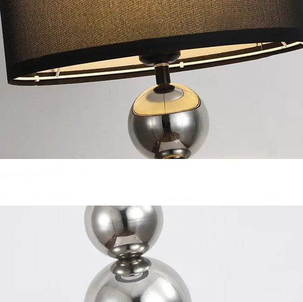 Close-up of a floor lamp with a black shade and metallic base on a white background.