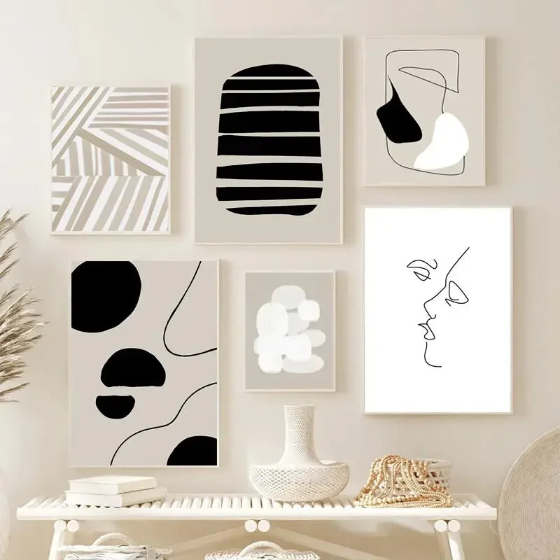 Set of six abstract black and white framed artworks on a wall above a shelf.