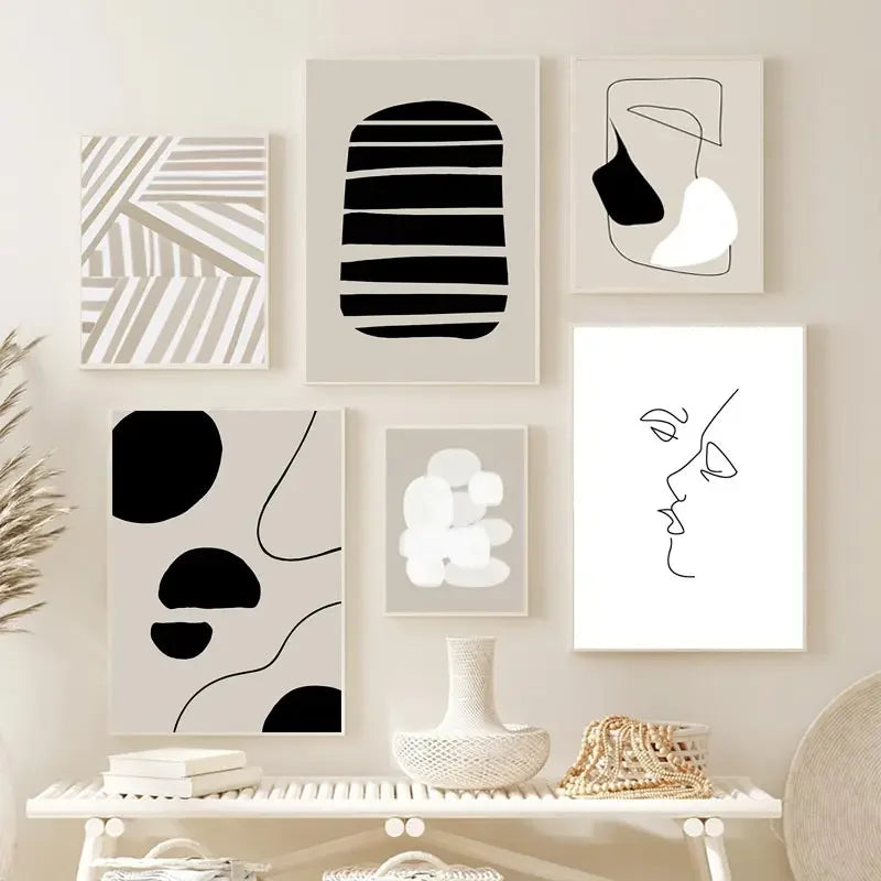 Set of six abstract black and white framed artworks on a wall above a shelf.