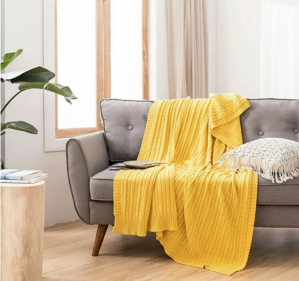 Yellow blanket draped over a gray sofa in a living room setting.