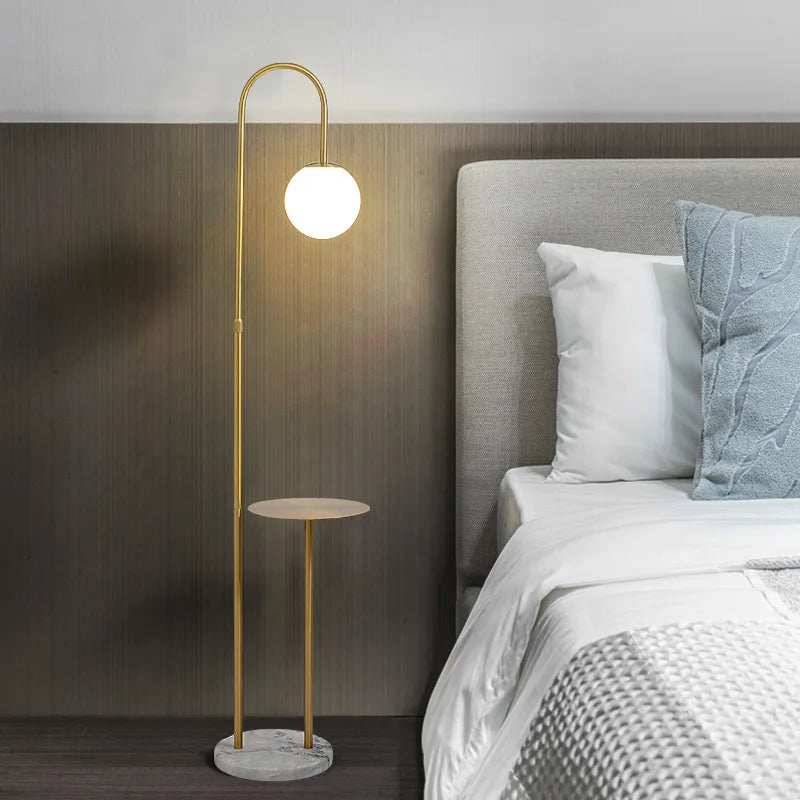 Modern floor lamp with a round table next to a bed in a bedroom setting.