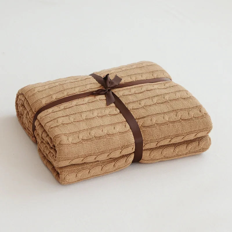 Folded brown textured blanket tied with a brown ribbon on a light gray background