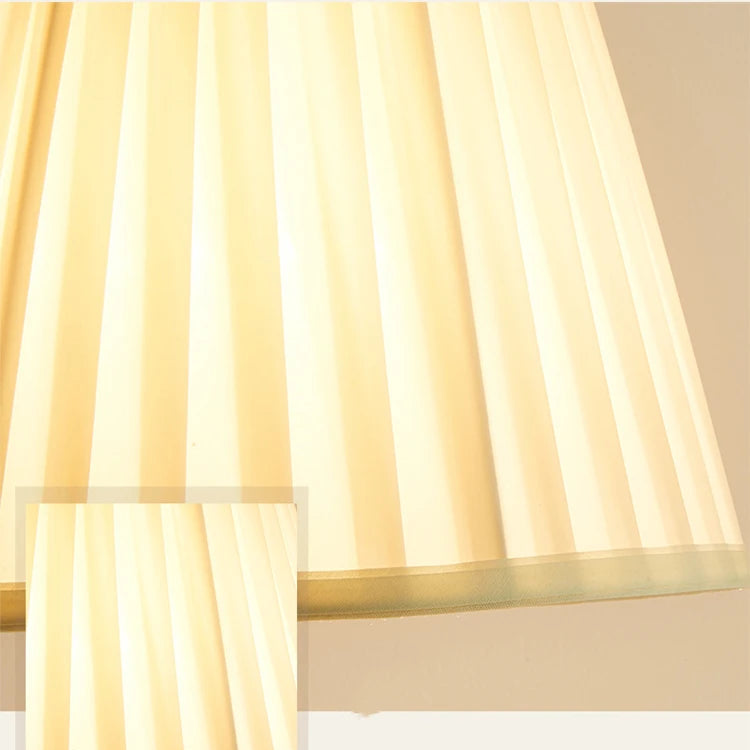 Close-up of a softly pleated fabric lampshade with warm light.