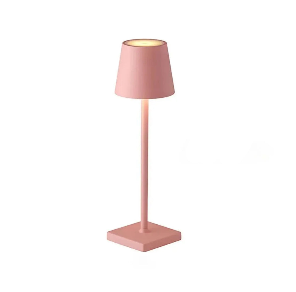 A pink table lamp with a square base on a white background