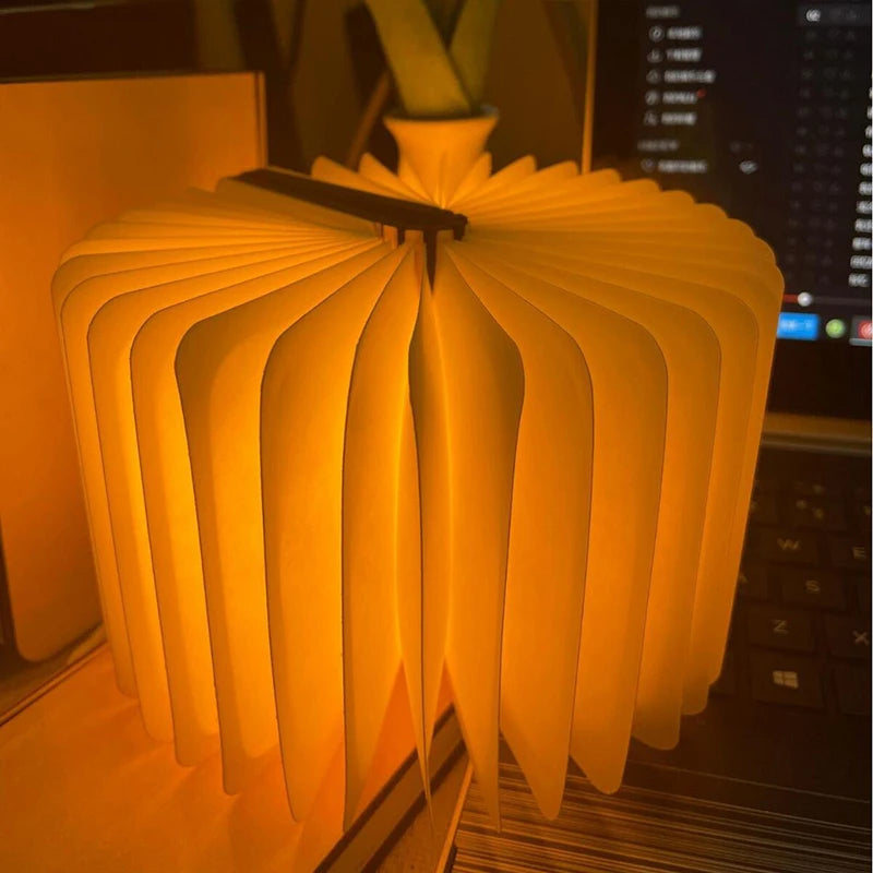 Book-shaped lamp emitting a warm glow in a blurred indoor setting