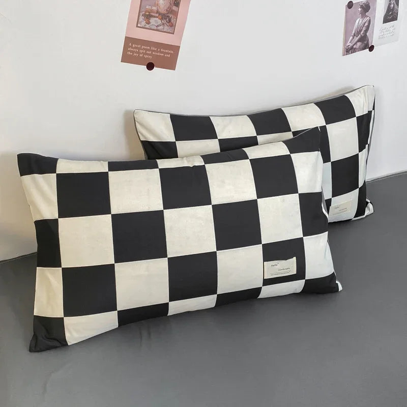 Two black-and-white checkered pillows on a grey surface.