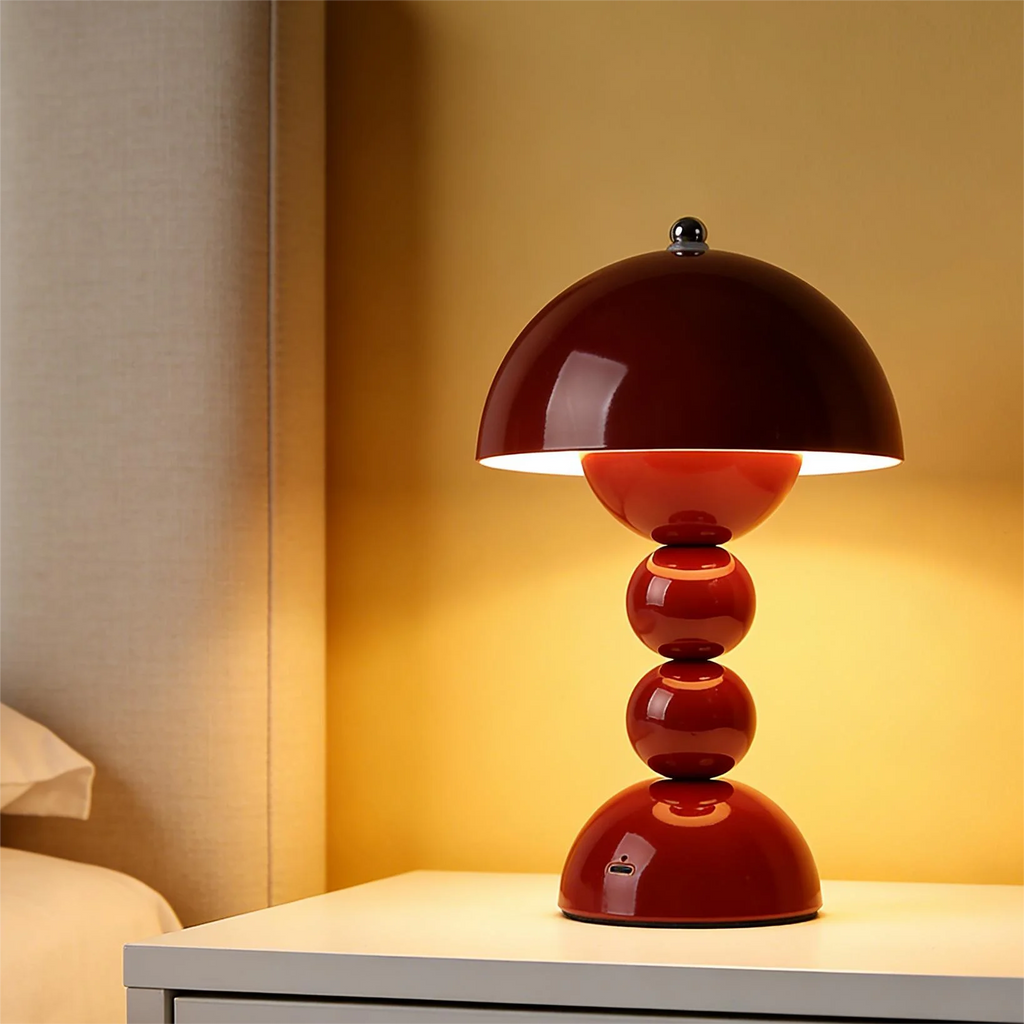 Red table lamp on a white surface with a warm glow against a beige wall.