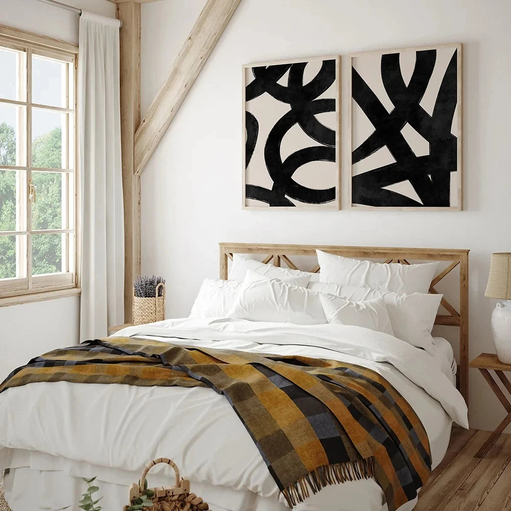 Bedroom with abstract wall art, plaid blanket, and wooden headboard.